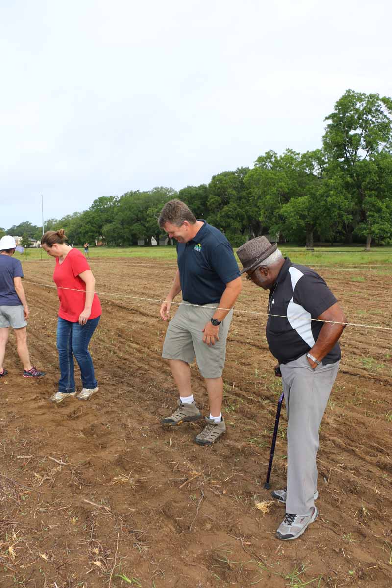 Volunteers and park staff tamp down soil after seeds have been planted