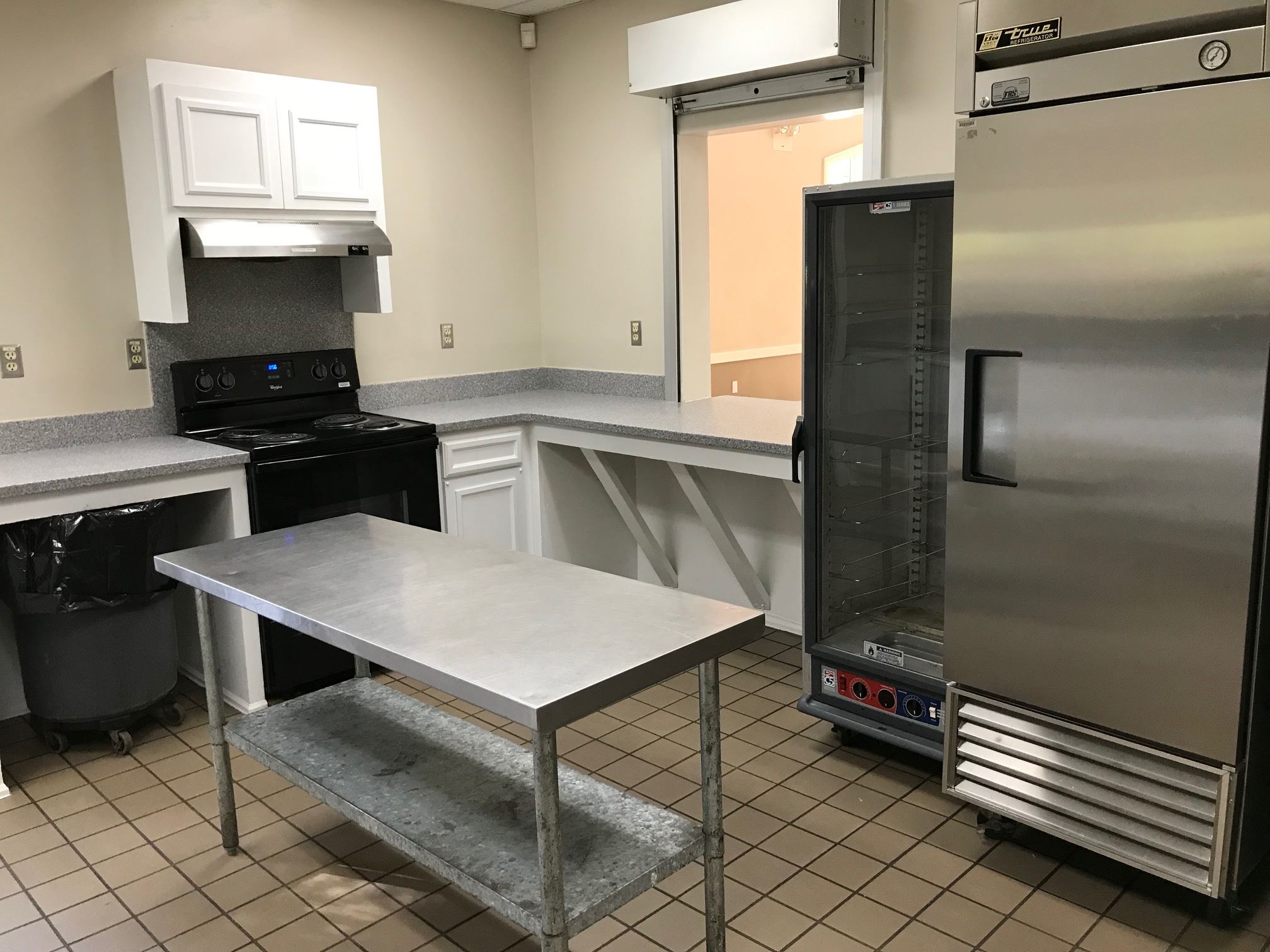 Kitchen with island stove, refrigerator, and warming appliance