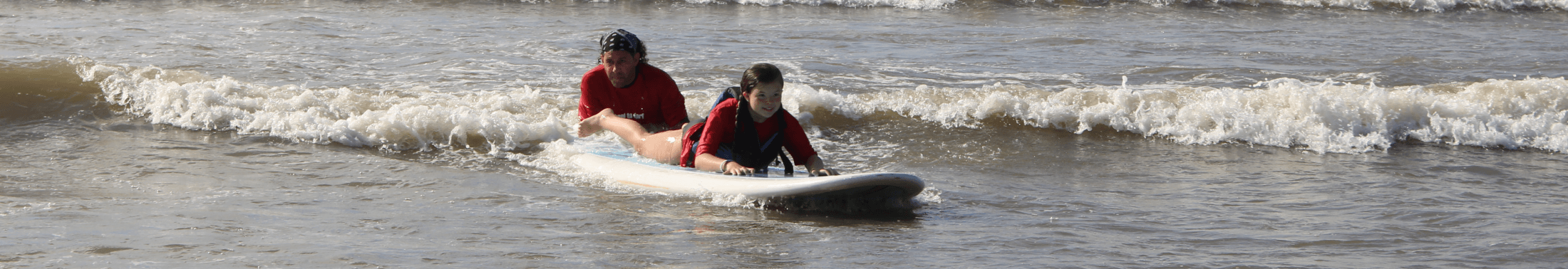 Man helps little girl learn to surf
