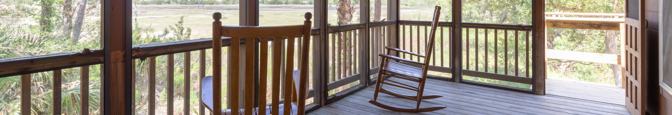 Rocking chairs sit on the screened in porch of the Cottages at James Island County Park