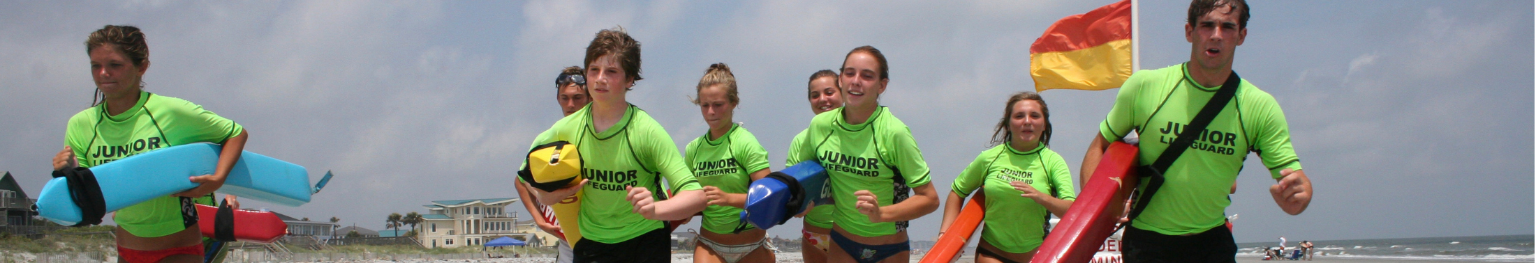 A group of junior lifeguards run on the beach