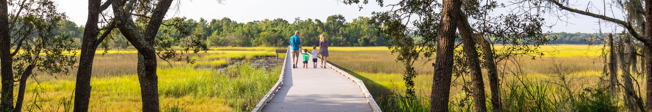 Family of four walks along the boardwalk at Stono River County Park