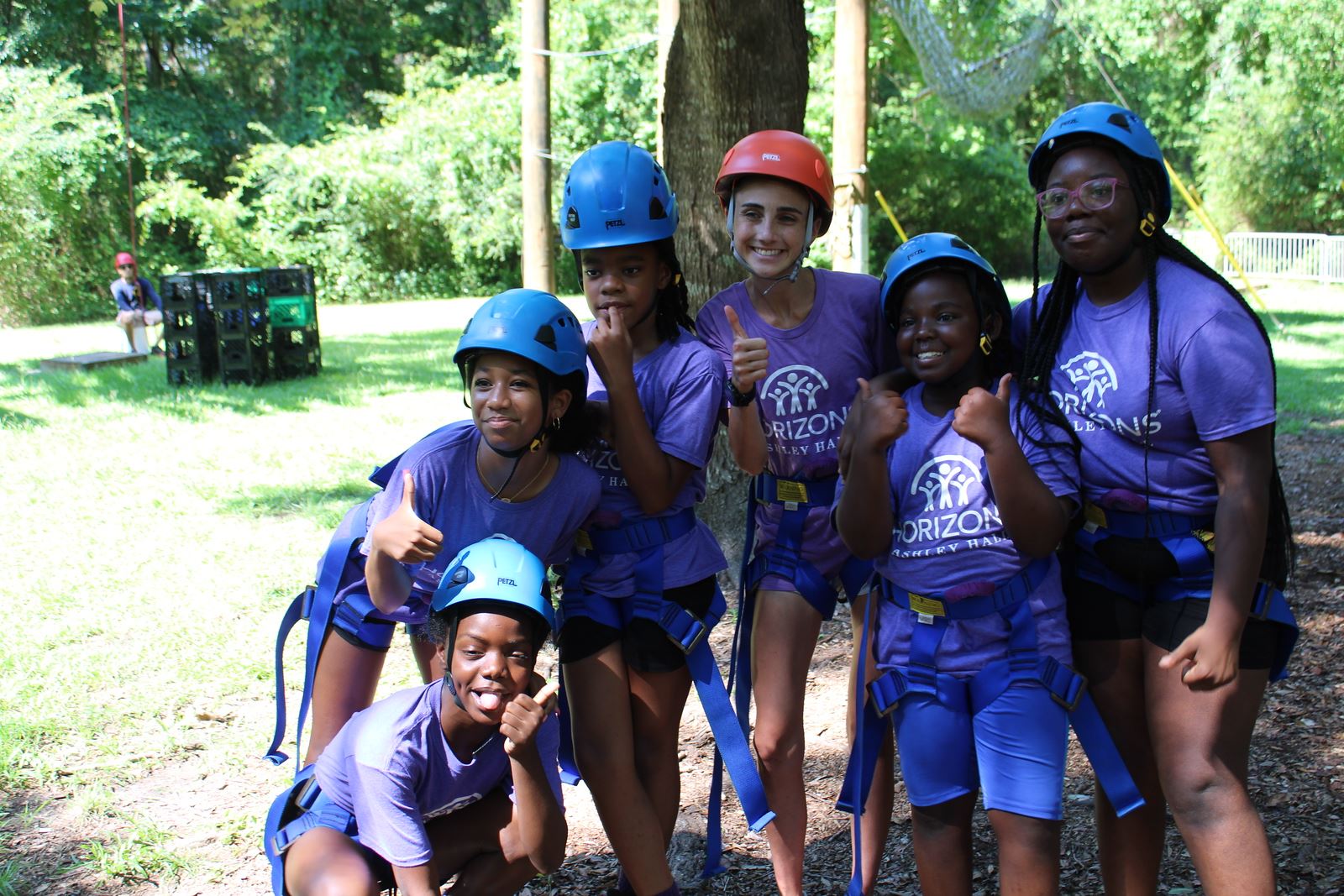 A group of girls pose for a photo while wearing helmets at the Challenge Course.