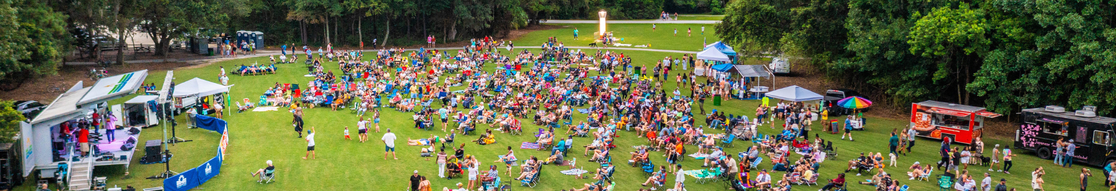 Aerial view of park visitors at an evening concert on the meadow