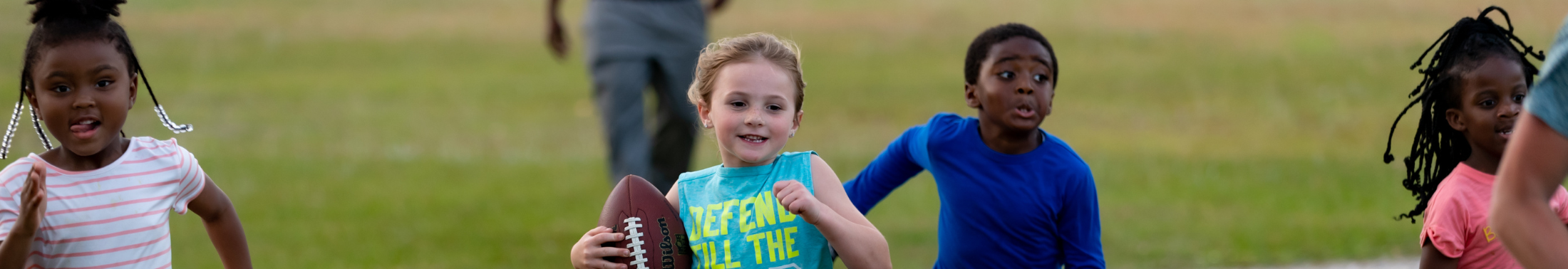 Photo of three children running plying football
