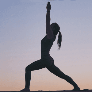 Silhouette of woman practicing yoga at twilight