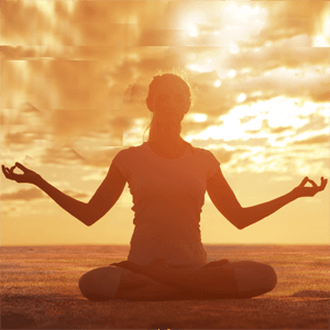 Silhouette of woman practicing yoga with the sunrise behind her