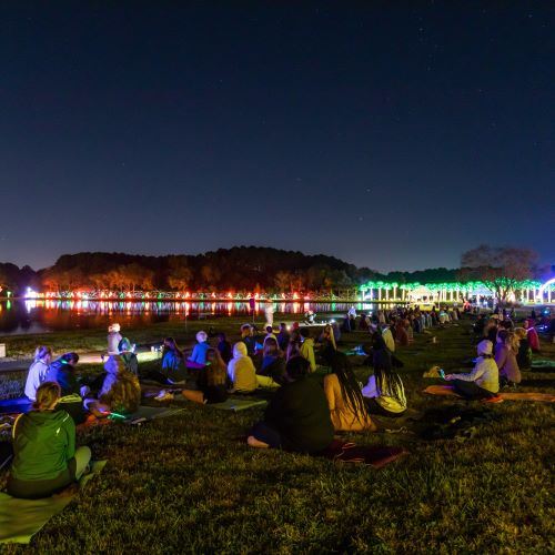 Yoga participants sitting on their mats with holiday lights in the background