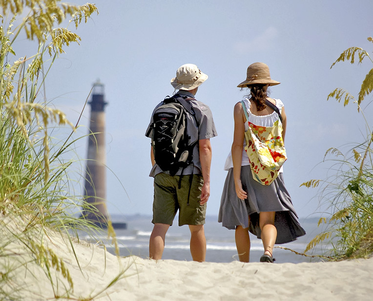 Couple on the Beach Looking at a Lighthouse in the Distance
