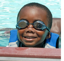 Young boy in swim goggles smiling at camera