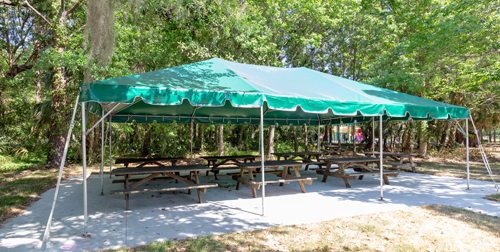 Funyard-Tent - green and white striped tent with picnic tables underneath