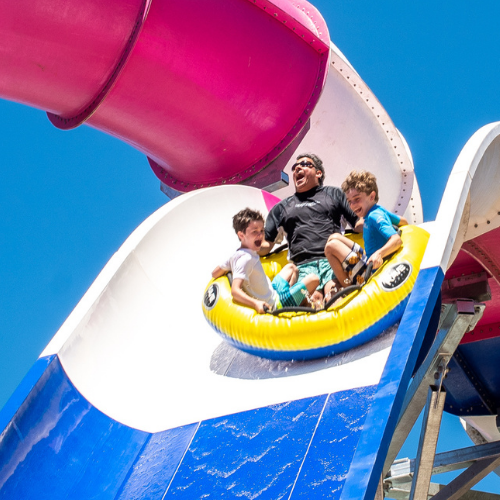 Man and two kids ride a waterslide