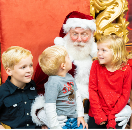 Three children visit with Santa Claus at the Holiday Festival of Lights.